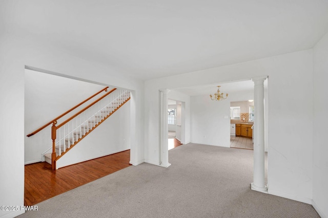 unfurnished living room featuring carpet flooring, a notable chandelier, and stairs