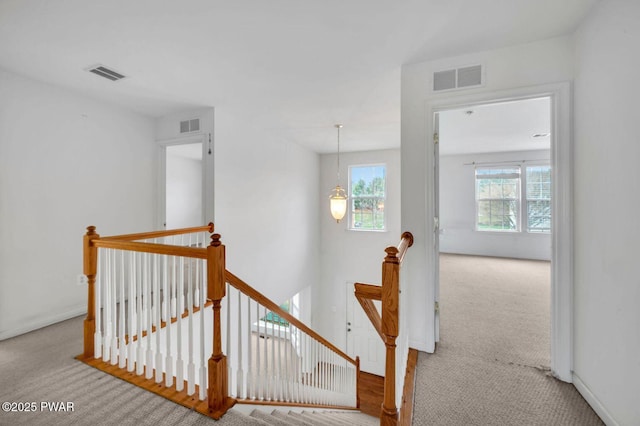 hall featuring an upstairs landing, visible vents, and carpet