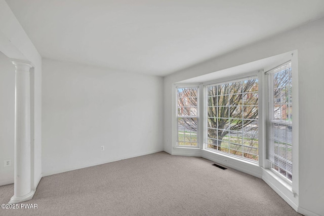 unfurnished room with baseboards, carpet flooring, decorative columns, and visible vents