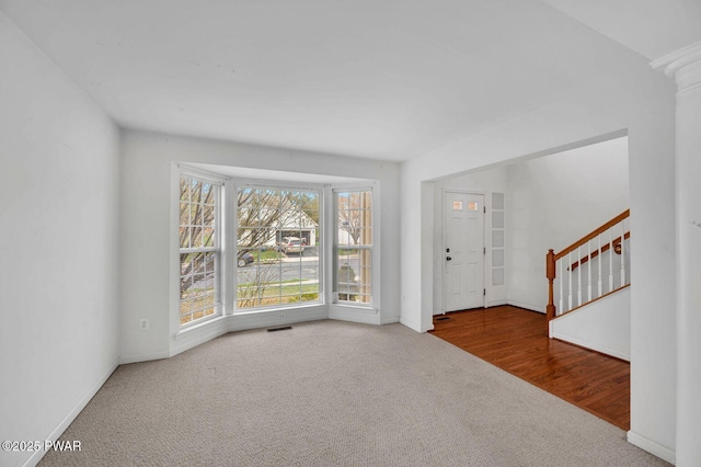 entryway with stairs, carpet flooring, visible vents, and baseboards