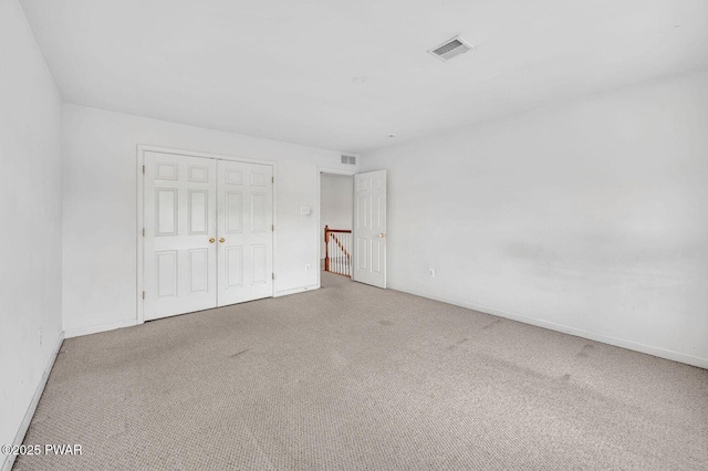 unfurnished bedroom featuring visible vents, baseboards, carpet flooring, and a closet