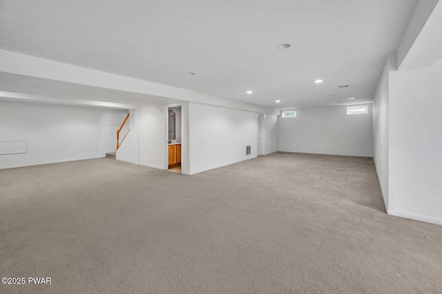 basement with light carpet, recessed lighting, stairway, and baseboards