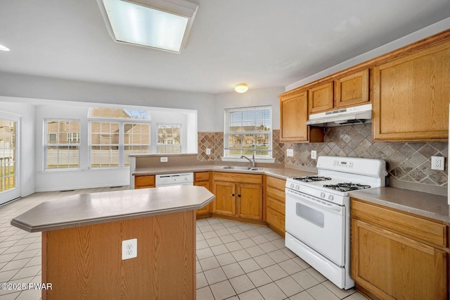 kitchen with under cabinet range hood, light tile patterned floors, a sink, and white appliances