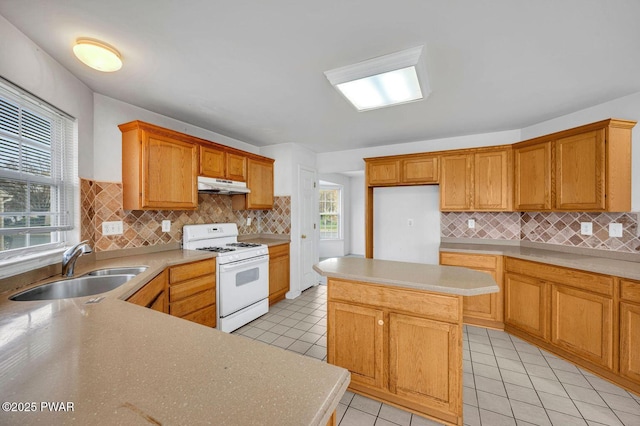 kitchen featuring light tile patterned floors, a sink, light countertops, under cabinet range hood, and white gas range oven
