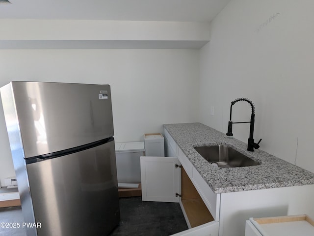 kitchen with light stone countertops, stainless steel fridge, a baseboard heating unit, sink, and white cabinets