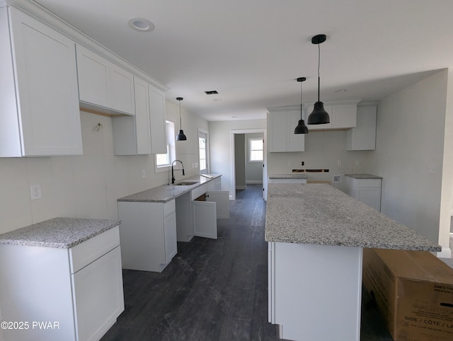 kitchen featuring a center island, white cabinetry, and sink