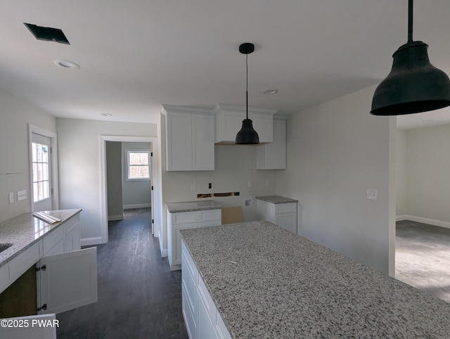 kitchen featuring white cabinetry, pendant lighting, light stone counters, and dark hardwood / wood-style floors