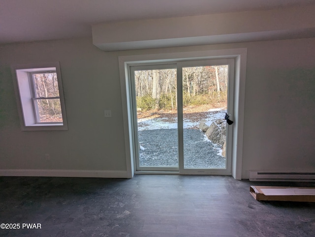 doorway to outside with concrete flooring, baseboard heating, and a wealth of natural light