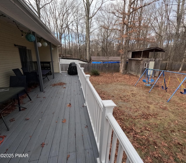 wooden deck with a storage unit, a playground, and a trampoline