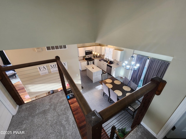 carpeted dining area with sink, a notable chandelier, and a high ceiling