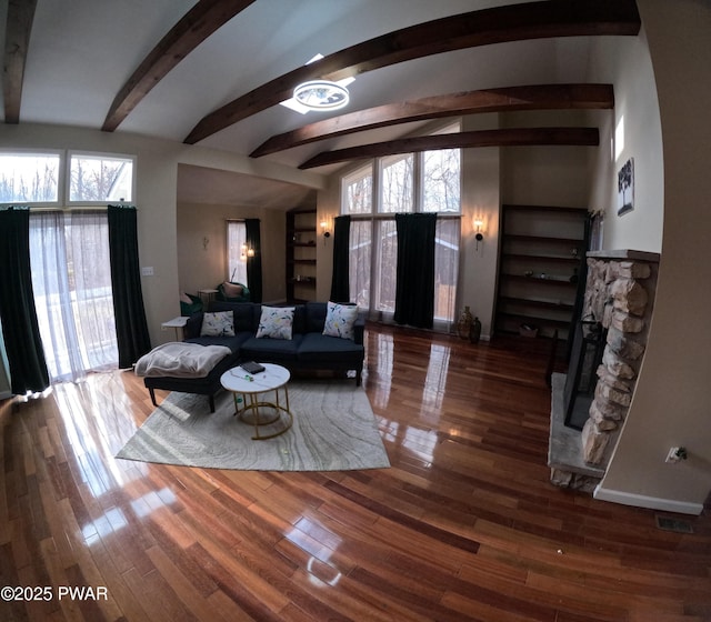 living room with dark hardwood / wood-style flooring, vaulted ceiling with beams, and a fireplace