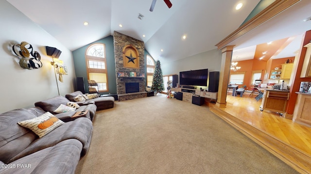 living room featuring ornate columns, a stone fireplace, light wood-type flooring, high vaulted ceiling, and ceiling fan with notable chandelier