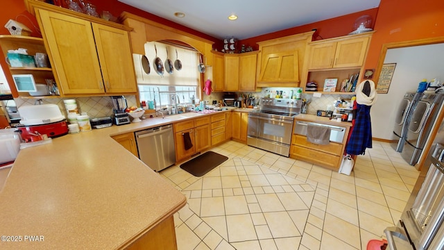 kitchen with separate washer and dryer, stainless steel appliances, decorative backsplash, sink, and light tile patterned flooring