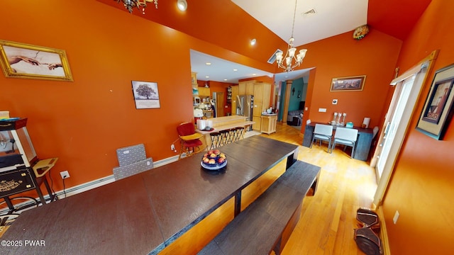 dining room featuring lofted ceiling, an inviting chandelier, and light hardwood / wood-style flooring