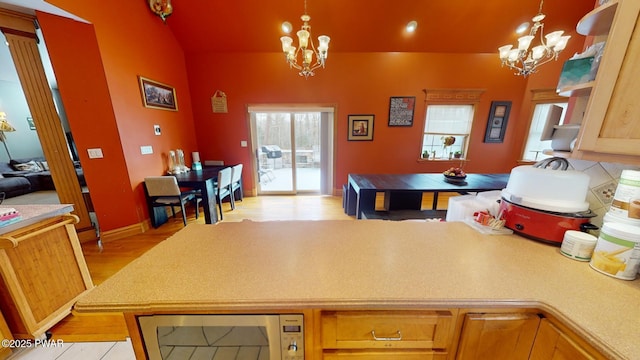 kitchen featuring stainless steel microwave, an inviting chandelier, light hardwood / wood-style floors, and hanging light fixtures