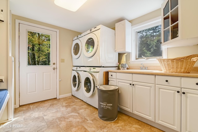 laundry room featuring stacked washer / drying machine, cabinets, and sink