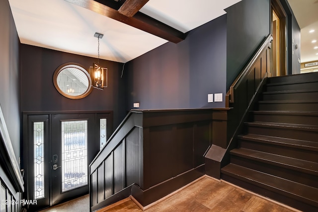 foyer entrance featuring beamed ceiling, a chandelier, and hardwood / wood-style flooring