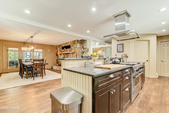 kitchen with a center island, island exhaust hood, light hardwood / wood-style floors, decorative light fixtures, and high end stainless steel range