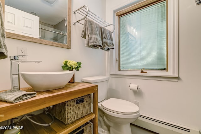 bathroom featuring an enclosed shower, toilet, baseboard heating, and sink