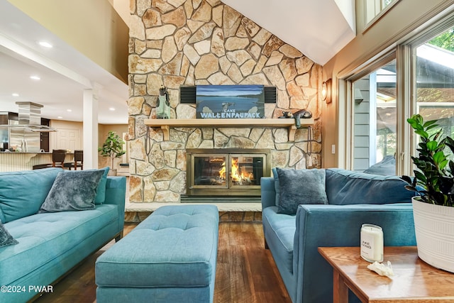 living room featuring dark hardwood / wood-style flooring, a stone fireplace, and lofted ceiling