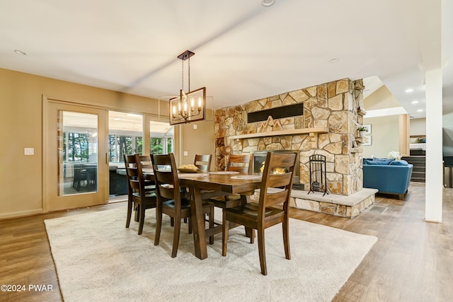 dining space featuring a fireplace, hardwood / wood-style floors, and a notable chandelier