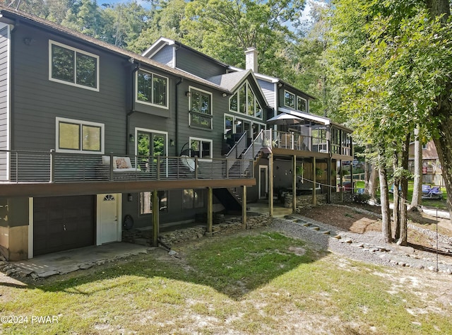 rear view of house featuring a lawn, a garage, and a deck