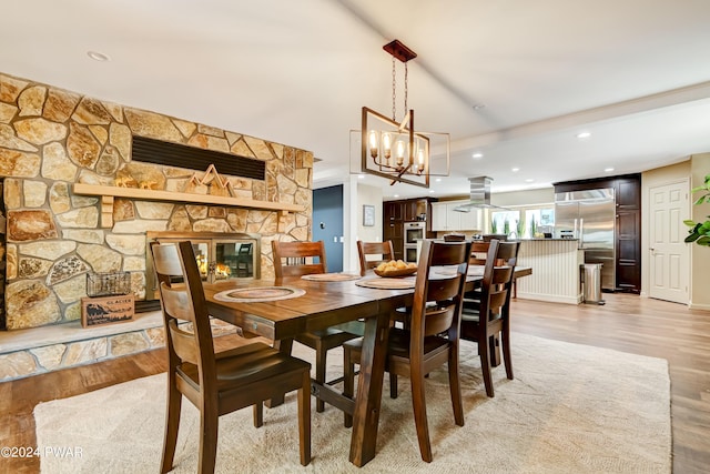 dining area featuring a notable chandelier, a fireplace, and light hardwood / wood-style flooring