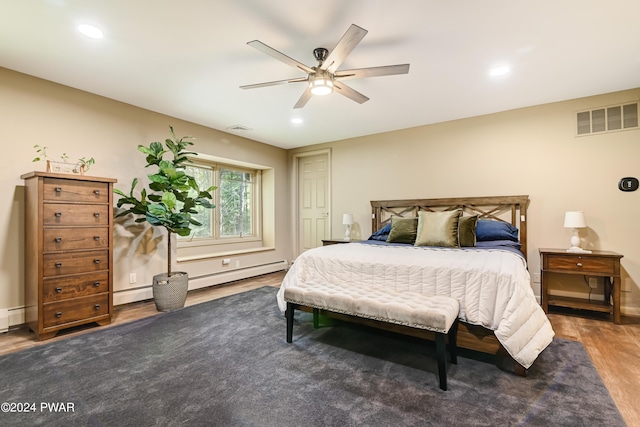 bedroom with ceiling fan, dark hardwood / wood-style flooring, and a baseboard heating unit