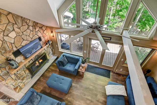 living room featuring plenty of natural light, ceiling fan, a stone fireplace, and lofted ceiling