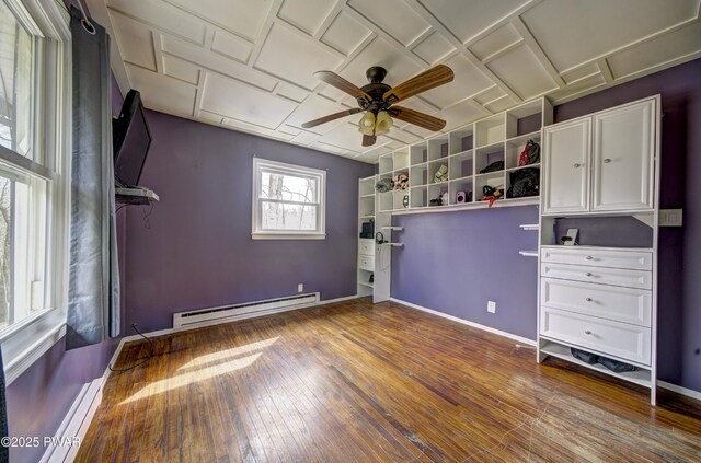 unfurnished bedroom with hardwood / wood-style floors, a baseboard heating unit, a baseboard radiator, ceiling fan, and baseboards