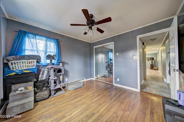 interior space with wood finished floors, crown molding, baseboards, ceiling fan, and a baseboard radiator
