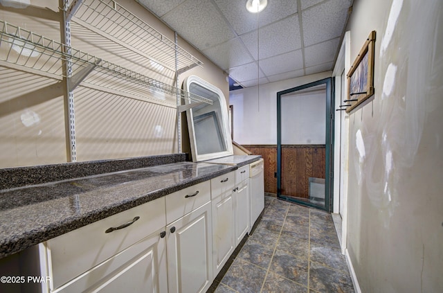 interior space with wainscoting, baseboards, and stone finish flooring