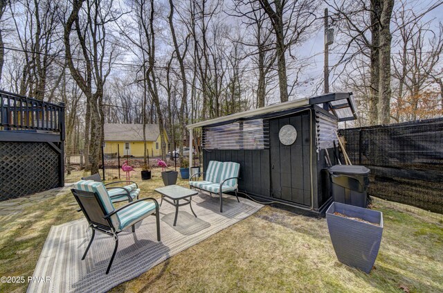 view of patio with an outdoor structure, a deck, a fenced backyard, and a shed