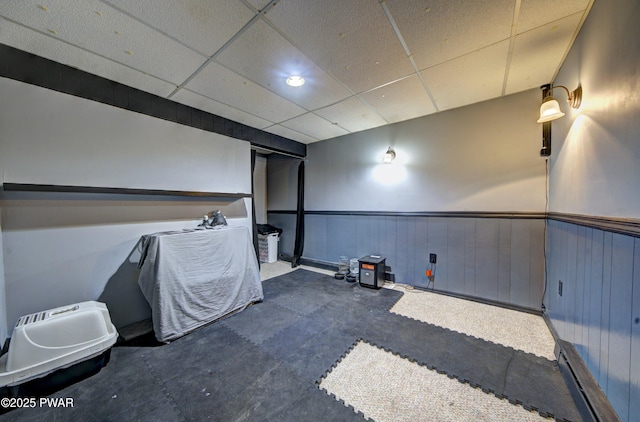 empty room featuring a paneled ceiling and a wainscoted wall