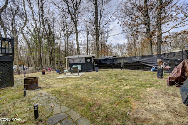 view of yard with a fire pit, an outbuilding, a fenced backyard, and a shed