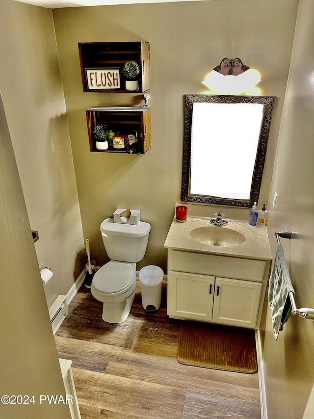 bathroom featuring vanity, toilet, wood-type flooring, and a baseboard heating unit