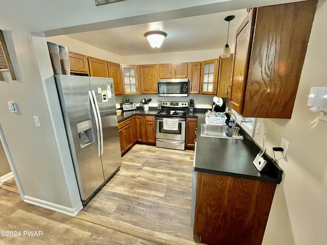 kitchen featuring pendant lighting, light wood-type flooring, sink, and appliances with stainless steel finishes