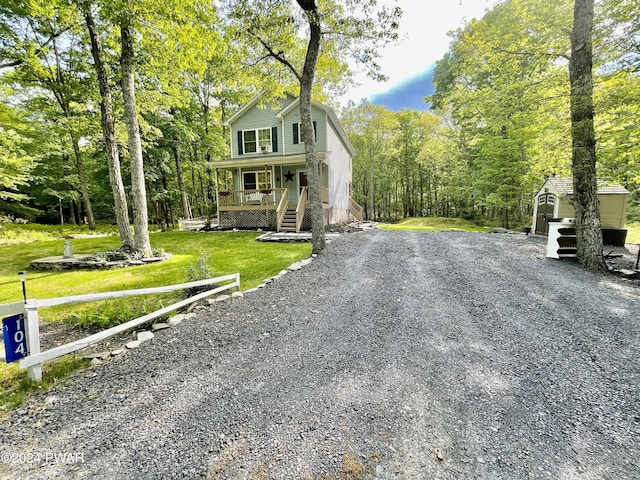 view of front of property with a front yard, a porch, and a shed