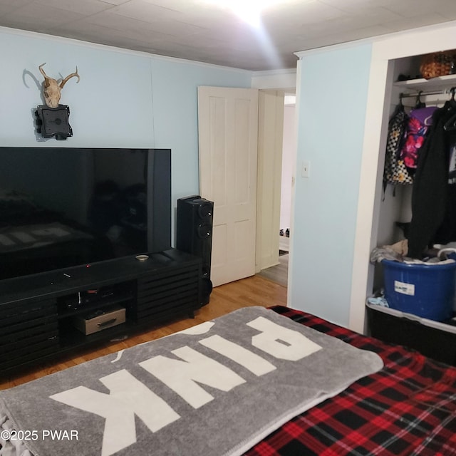 bedroom with hardwood / wood-style flooring, ornamental molding, and a closet