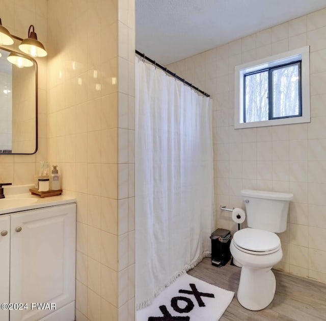 bathroom with vanity, toilet, tile walls, and curtained shower