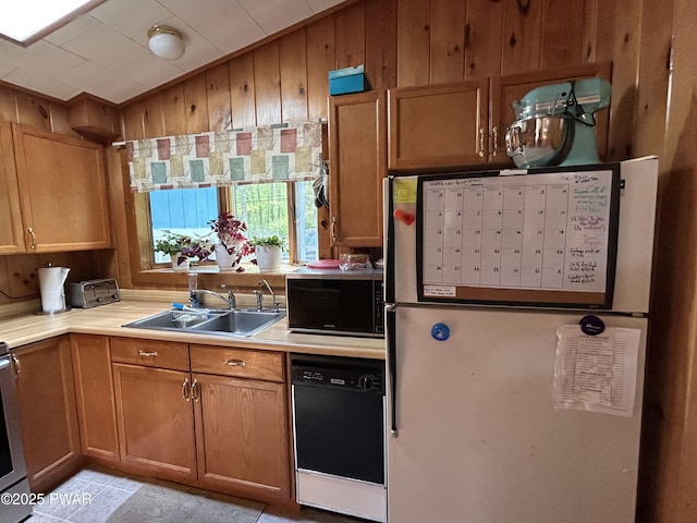 201 Oak Hill Rd, Hawley, PA 18428 - kitchen featuring freestanding refrigerator, black dishwasher, a sink, wood walls, and light countertops