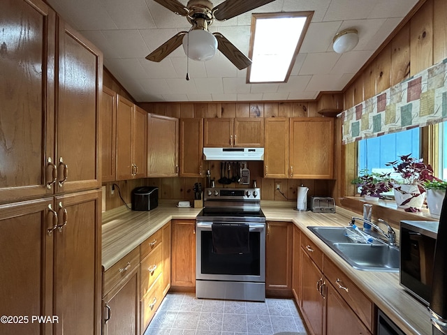 201 Oak Hill Rd, Hawley, PA 18428 - kitchen with stainless steel electric range oven, under cabinet range hood, light countertops, a sink, and brown cabinetry