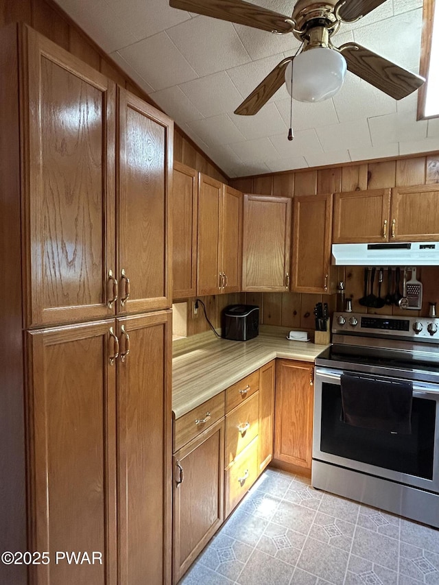 201 Oak Hill Rd, Hawley, PA 18428 - kitchen with electric stove, under cabinet range hood, light countertops, ceiling fan, and brown cabinetry