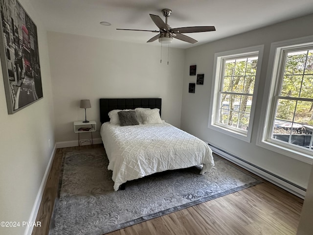 bedroom with ceiling fan, wood-type flooring, and a baseboard radiator