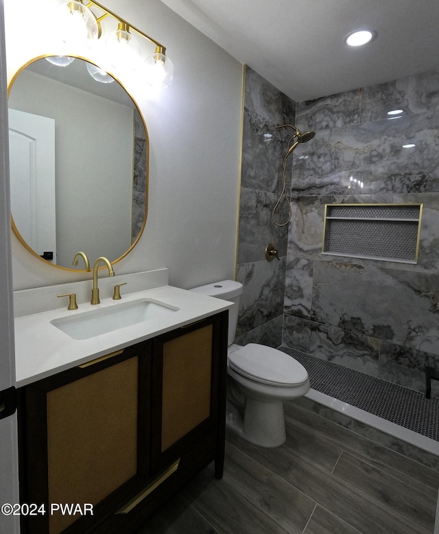 bathroom featuring toilet, vanity, and tiled shower