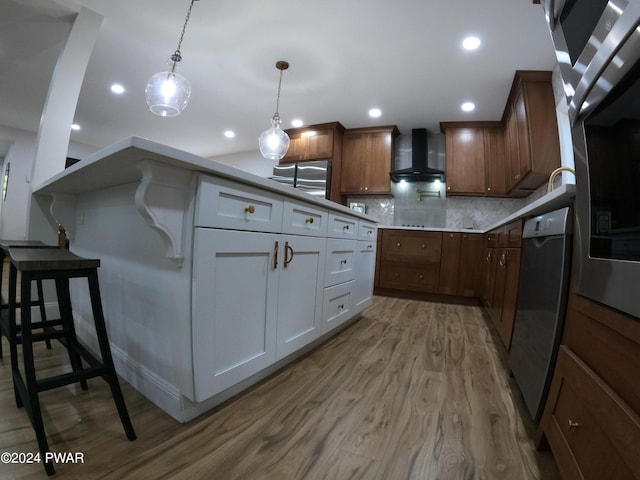 kitchen with white cabinetry, wall chimney exhaust hood, stainless steel dishwasher, decorative light fixtures, and decorative backsplash