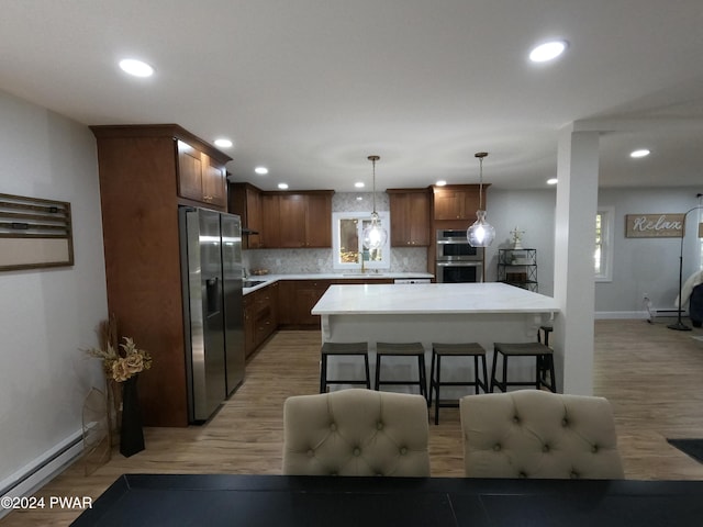 kitchen featuring pendant lighting, tasteful backsplash, appliances with stainless steel finishes, a baseboard radiator, and a kitchen island