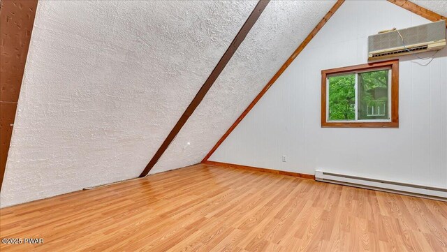 122 Westfall Dr, Dingmans Ferry, PA 18328 - bonus room featuring lofted ceiling, wood finished floors, a wall mounted air conditioner, a textured ceiling, and a baseboard radiator