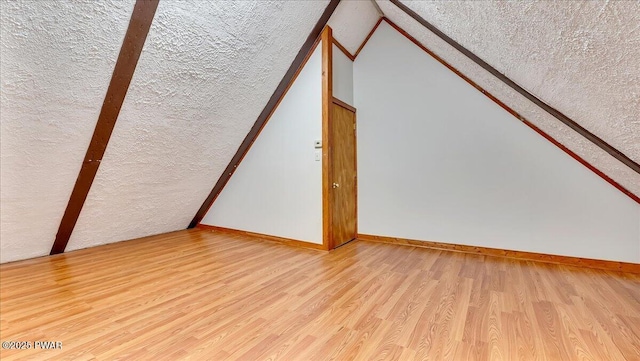122 Westfall Dr, Dingmans Ferry, PA 18328 - bonus room featuring a textured ceiling, vaulted ceiling, wood finished floors, and baseboards