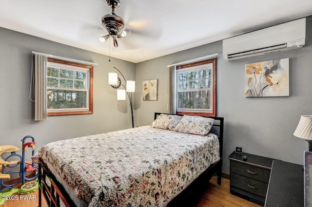 bedroom featuring ceiling fan, wood-type flooring, and a wall mounted AC